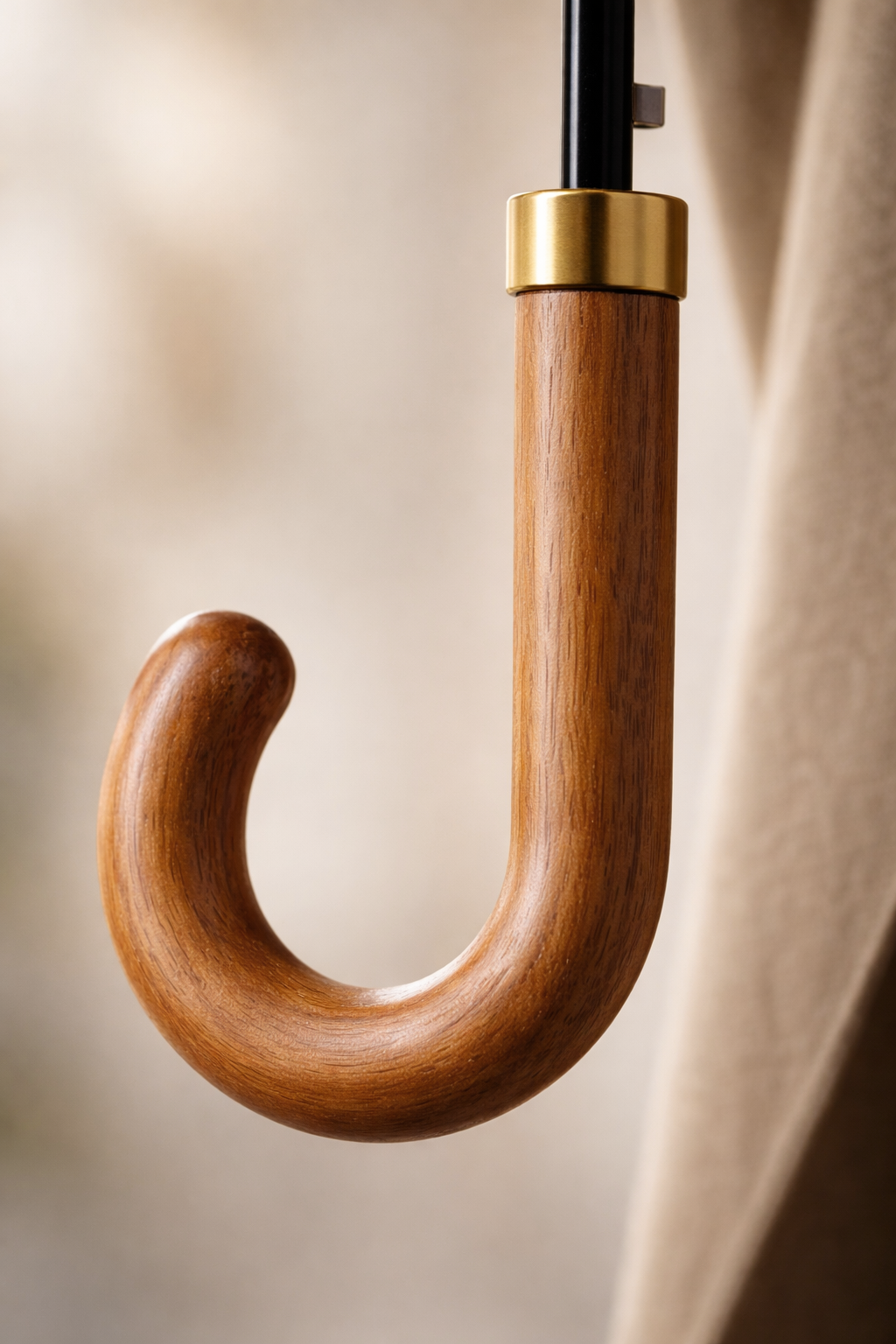 Close-up of smooth oak wood curved handle with gold collar and polished shaft fitting.