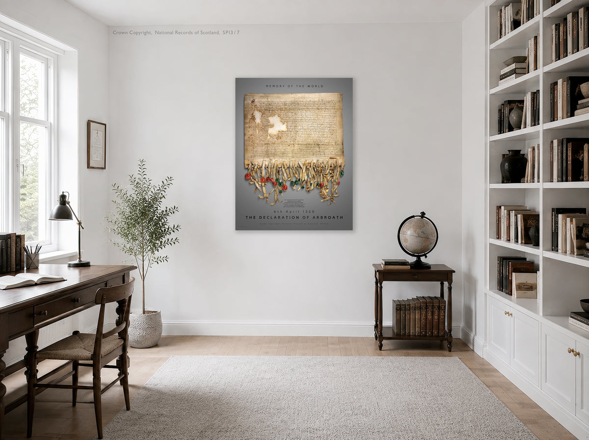 Illustrative bright study and library interior showing the Pewter Burnished Gold Declaration of Arbroath print on a pale wall between a writing desk and built-in bookshelves.