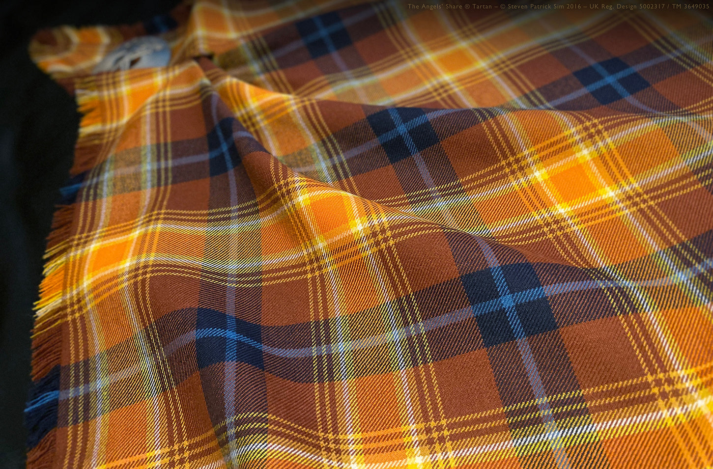 Full-length view of the Angels’ Share Scotch Whisky tartan fringed fly plaid draped over a dress form, displaying the complete sett, scale, and flowing fringe.