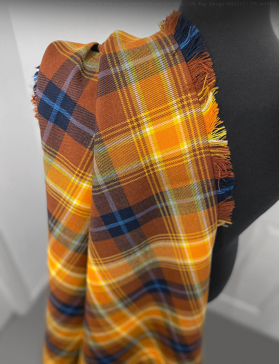 Fringed fly plaid in Angels’ Share tartan pinned and styled over shoulder with brooch. Draped traditionally over the shoulder, this fly plaid is shown pinned with a classic brooch to highlight ceremonial wear styling.