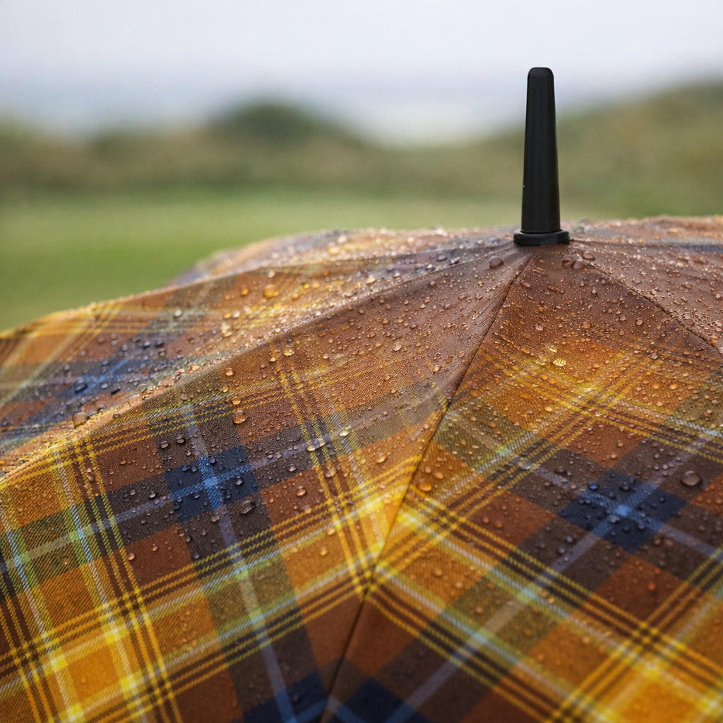 Close-up of the Angel’s Share tartan umbrella canopy covered in rain droplets, highlighting the warm whisky-inspired check pattern and textured fabric.