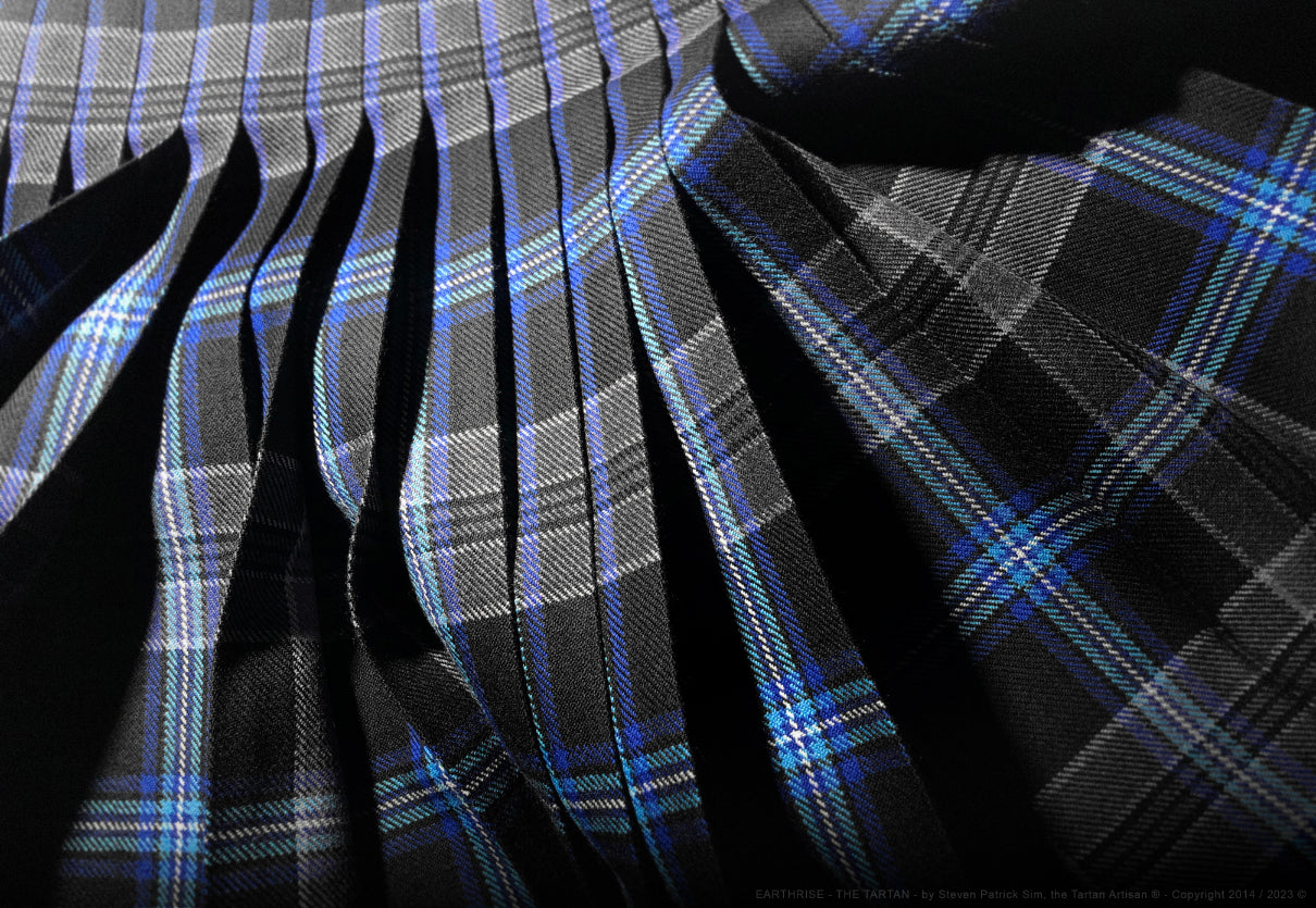 A dynamic angled view of the Earthrise kilt pleats, emphasising movement, depth, and the contrast between black, grey, and blue.