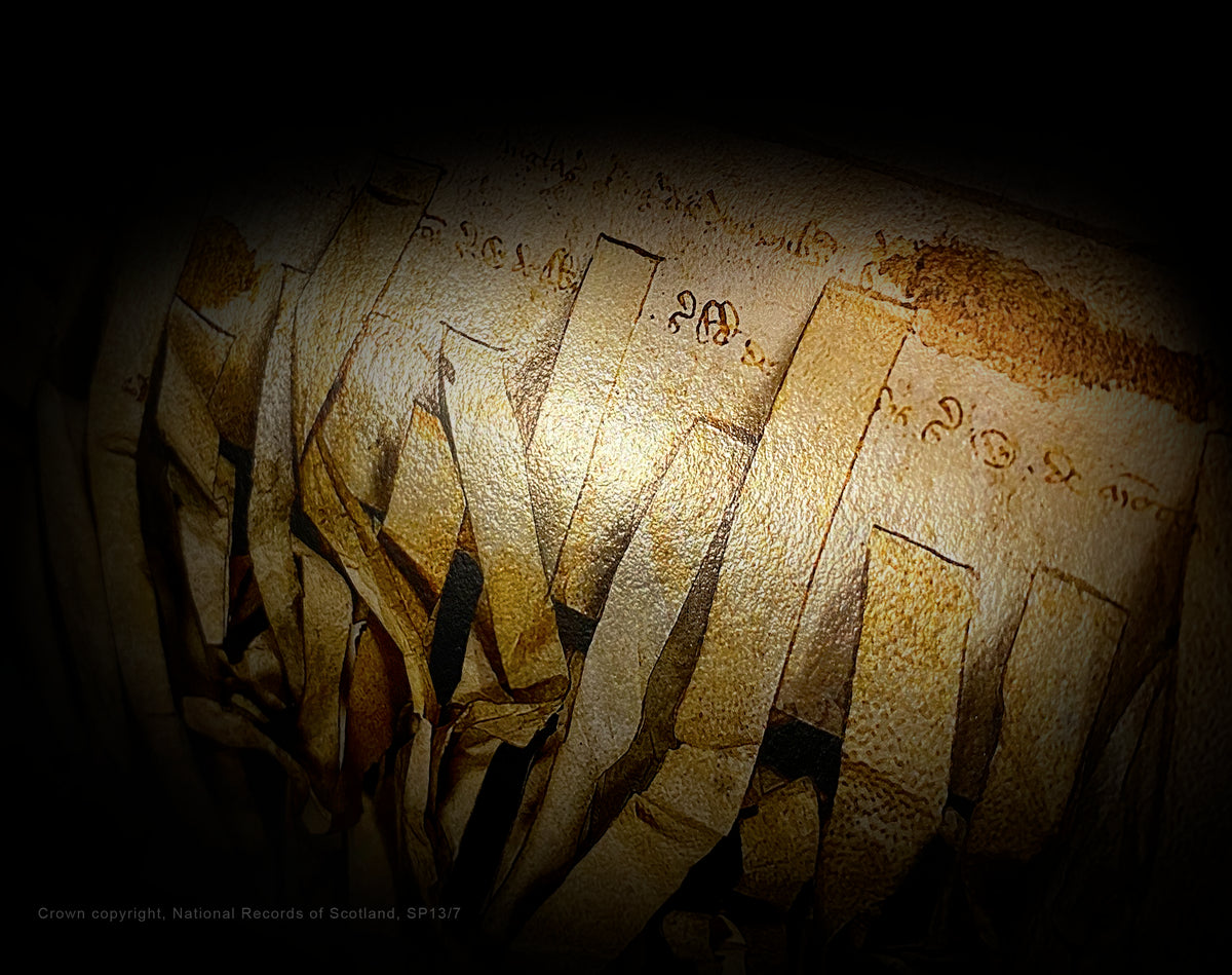 Close-up of a rolled Declaration of Arbroath Burnished Gold print, showing parchment-tag imagery and metallic reflections against a dark background.