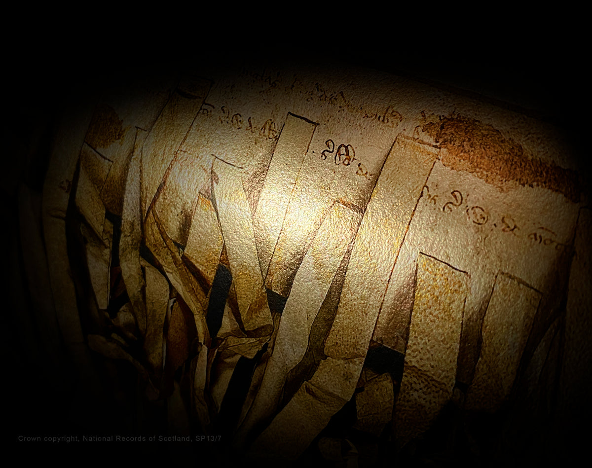 Close-up of a rolled Declaration of Arbroath Burnished Gold print, showing parchment-tag imagery and metallic reflections against a dark background.