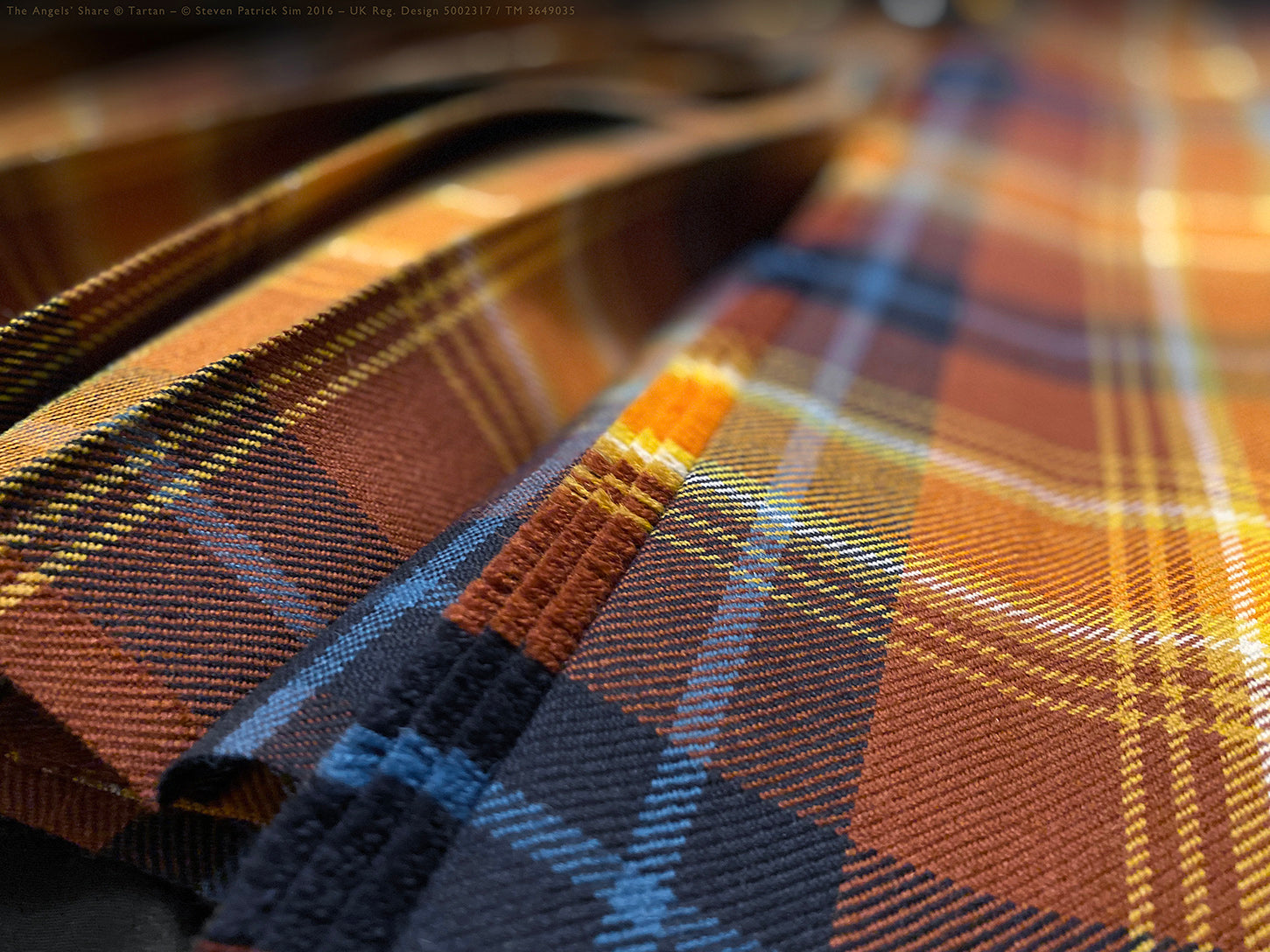 Cinematic view of the Angels’ Share® kilt in, capturing the lustre of the tartan’s spiritual colour palette, including the dark navy coal and cool blue of Scottish aqua. Whisky made wearable — movement in cloth and light.