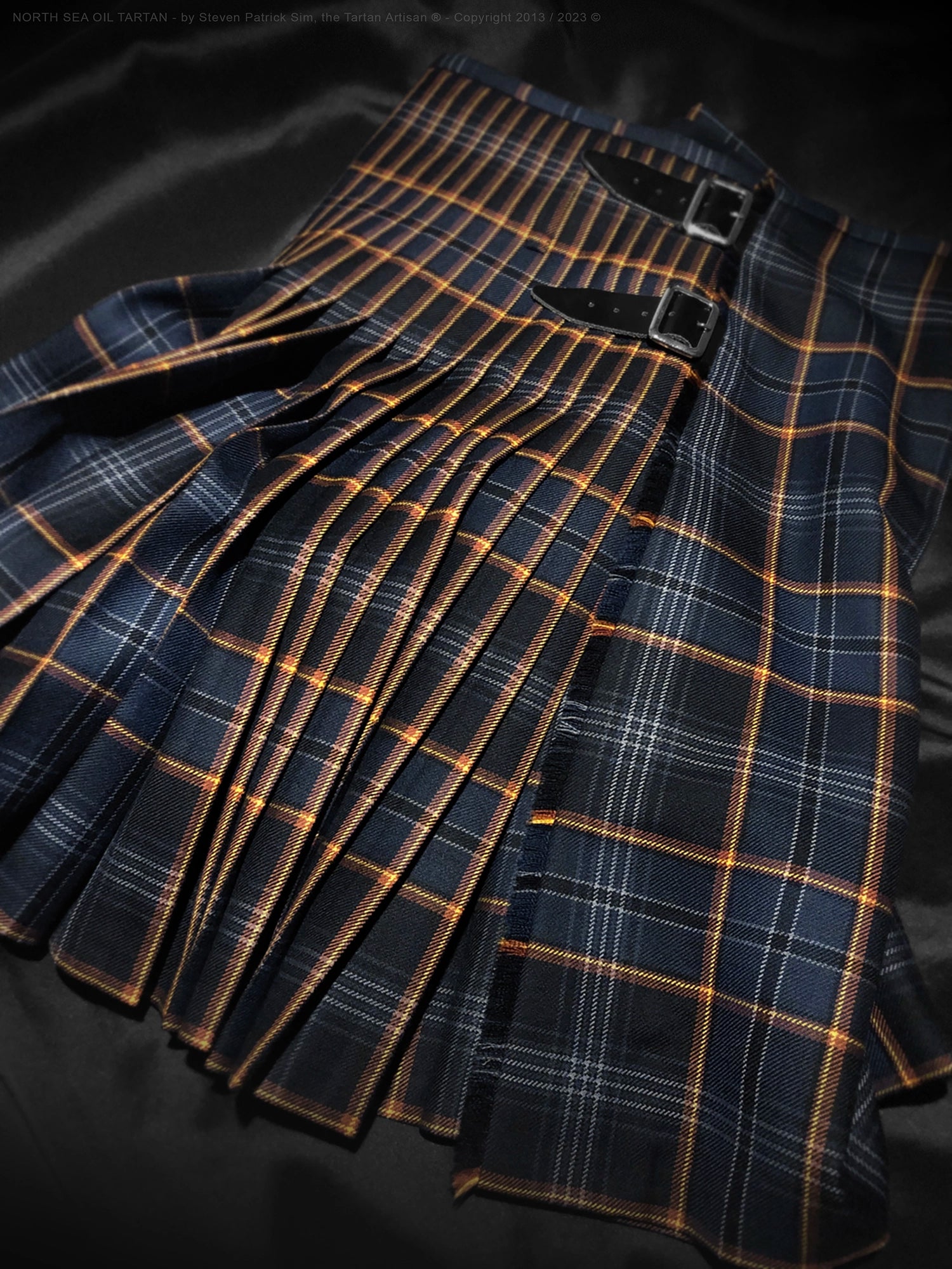 Rear view detail of the North Sea Oil tartan kilt focusing on the pleated back, leather straps, and buckle fastening, demonstrating traditional kilt construction and finish.