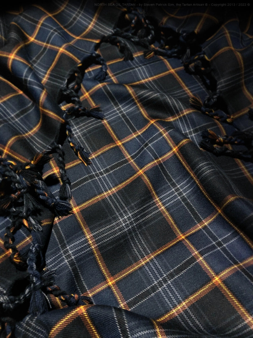 Handwoven fabric detail of the North Sea Oil tartan showing the purlded and knotted interplay of colour, thread structure, and traditional weaving technique.