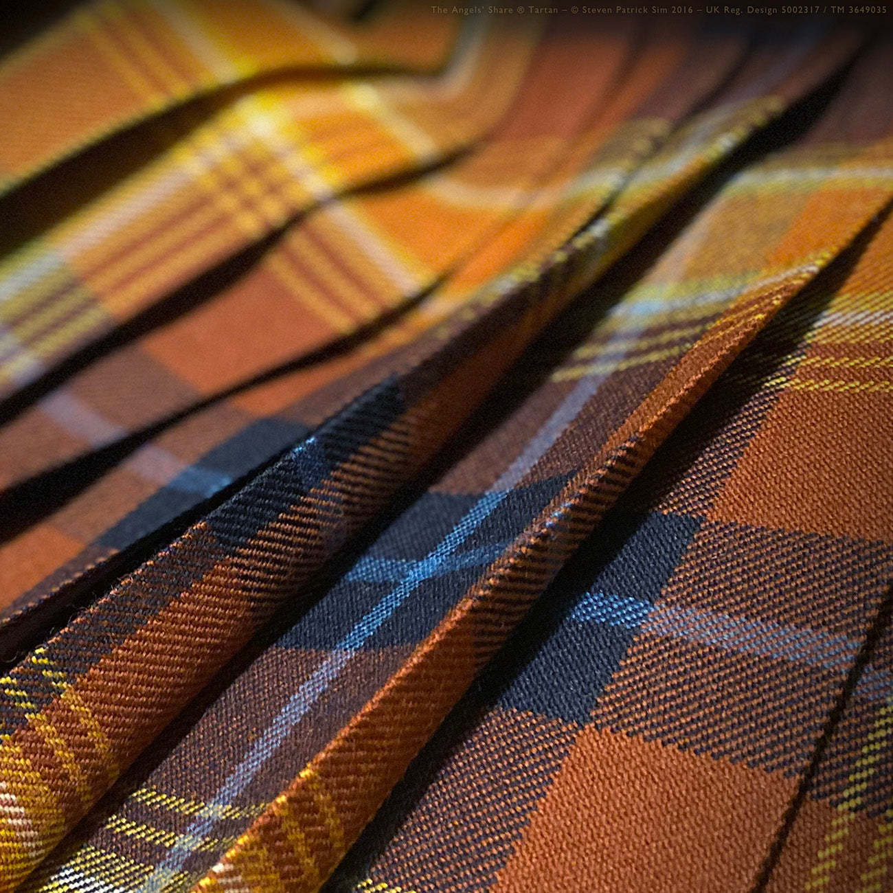 A rich detail of the kilt’s pleats capturing deep navy and Scots watery blue tones. Pleated to the traditional sett. Plus the warmth of the dram — woven deep in the sett.